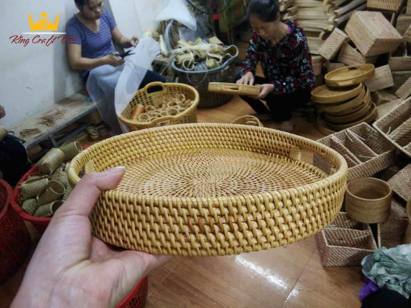 Artisan weaving rattan strips to create a handwoven serving tray