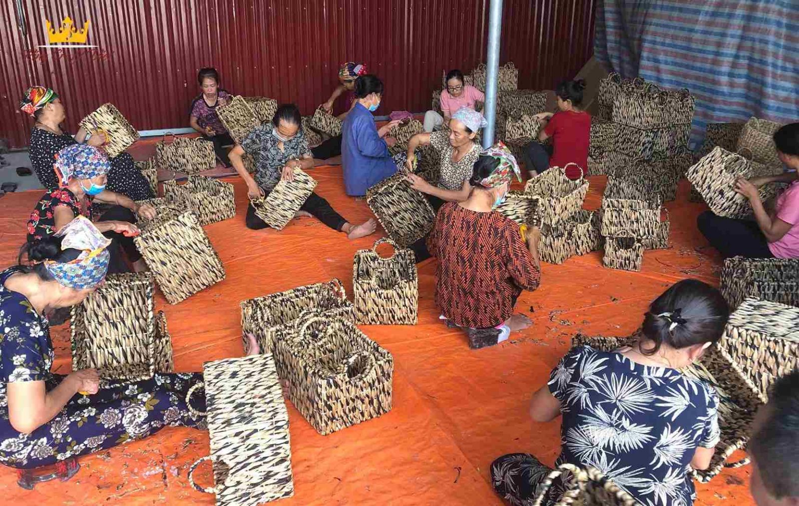 Vietnamese artisans hand weaving storage baskets in factory